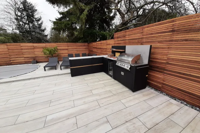 contemporary outdoor kitchen with cedar wood fencing next to pool