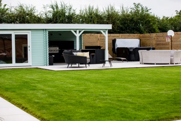 summerhouse with roofed outdoor kitchen and hot tub in Warwickshire garden