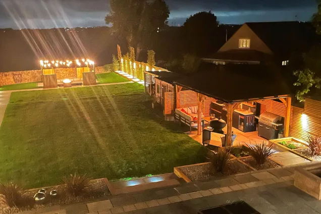 garden at night with roofed outdoor kitchen and lights on in Sheffield