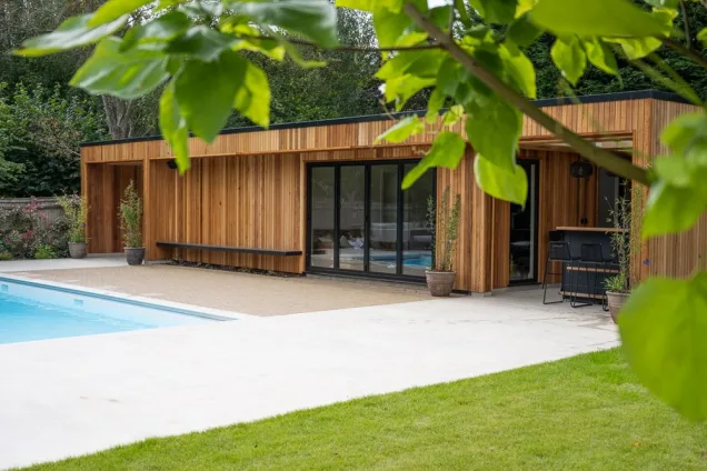 Outdoor kitchen under garden room next to pool