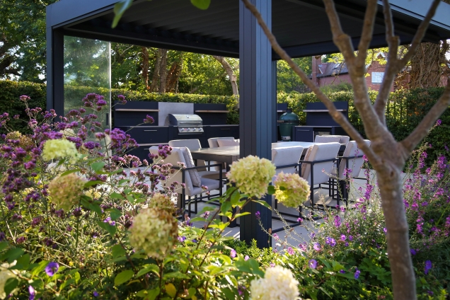 Planter and flowerbed next to outdoor kitchen area in Reigate