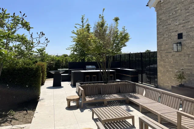 slatted wooden bench seating area overlooking stylish outdoor kitchen on patio in Little Waltham, Chelmsford, Essex