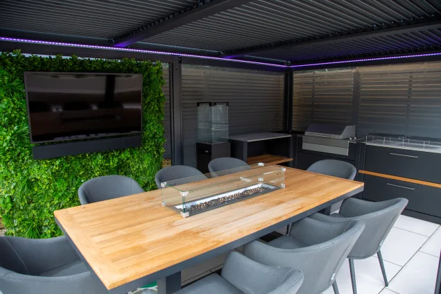 Outdoor kitchen in Leicestershire under pergola with seating area and tv
