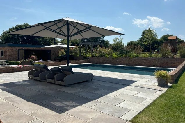 Outdoor kitchen in saffron walden with canopy next to large outdoor pool