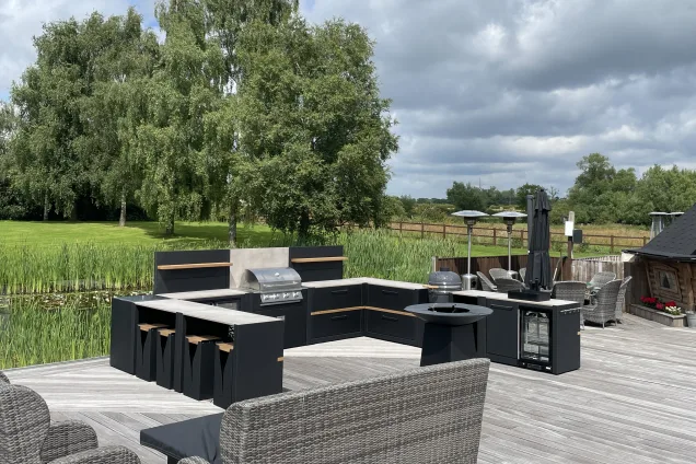 Outdoor kitchen in Stafford on large decking area with chefs anvil and bar table and stools cabinets and bull gas bbq
