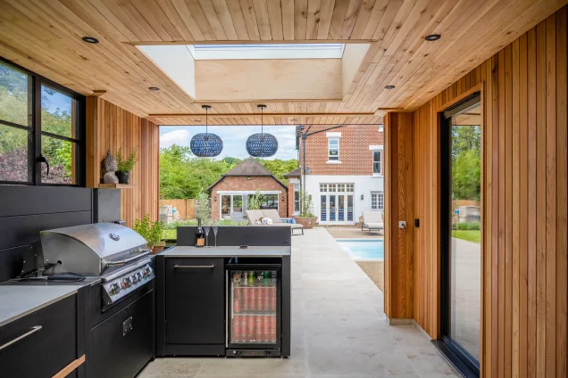 Outdoor kitchen with fridge and bin under standing bar and Bull gas grill.