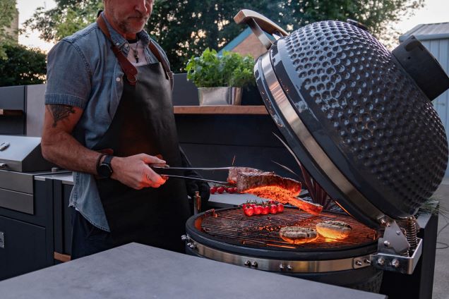 Outdoor kitchen with man cooking steak on gusto charcoal bbq