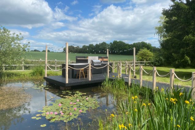 Outdoor kitchen on pontoon over pond with bbq and storage units