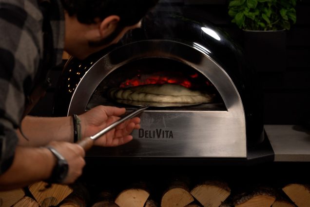 person turning calzone pizza in pizza oven