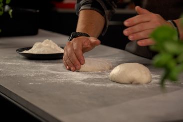 person preparing pizza dough