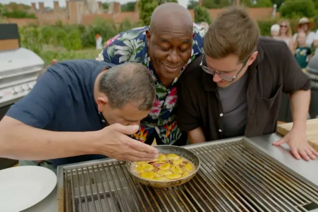 Ainsley and guest chefs smell a dish cooking in a Grillo kitchen