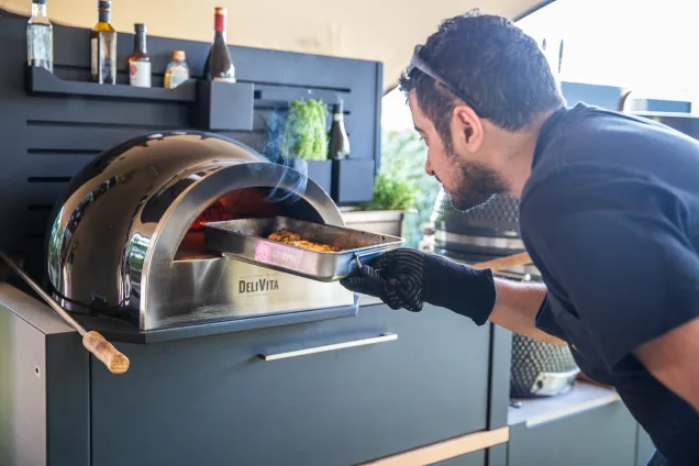 sorted food man putting food into grillo pizza oven in outdoor kitchen