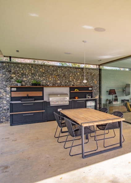 outdoor kitchen in grand designs house with cobbled wall behind