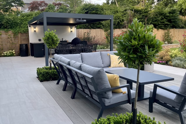 outdoor kitchen on patio under pergola and outdoor seating area on decking