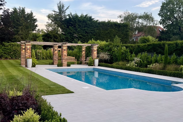 large landscaped garden with outdoor pool surrounded by patio and decking