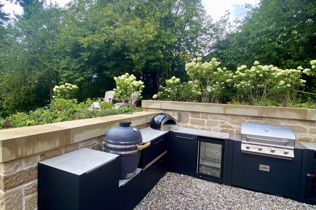 outdoor kitchen in large mature garden with charcoal, gas and wood fired bbqs and storage units