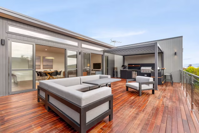 outdoor kitchen under pergola on stained decking and seating area