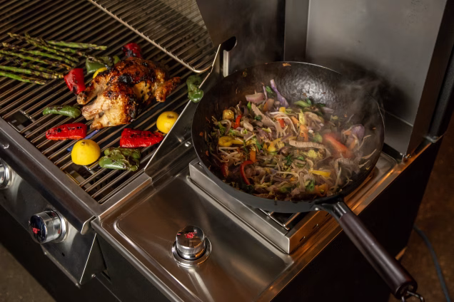 wok on sideburner next to veg on grill station