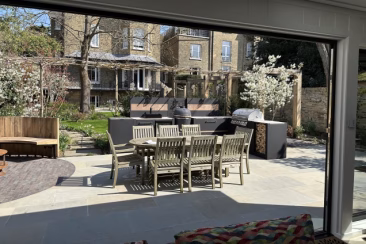 Looking out of a garden building in a London 4-storey period townhouse garden landscaped by Garden Club London, with an outdoor kitchen centre of frame