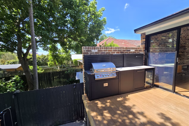 A view across leafy residential backyards in Naremburn NSW, with a Grillo outdoor kitchen next to large patio doors on a raised deck in the foreground