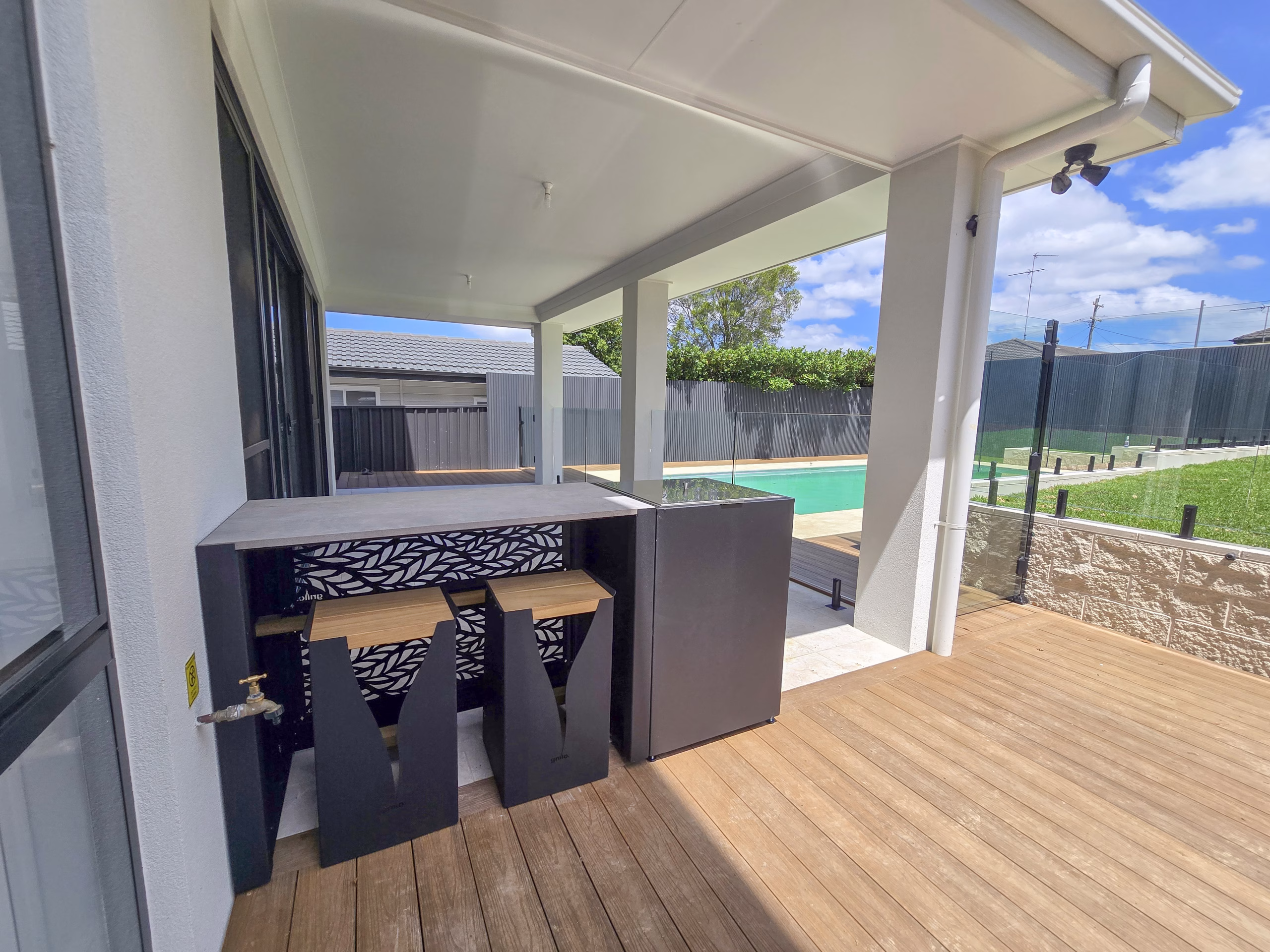 The seating of an outdoor kitchen area, showing the Habitat patterned rear fascia, in a landscaped garden in Old Toongabbie, Sydney