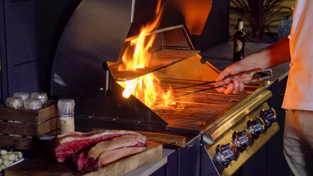 person cooking flaming steak on bull gas grill