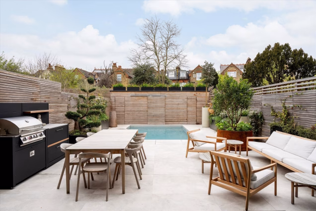 outdoor kitchen in hardscaped garden with pool and seating areas