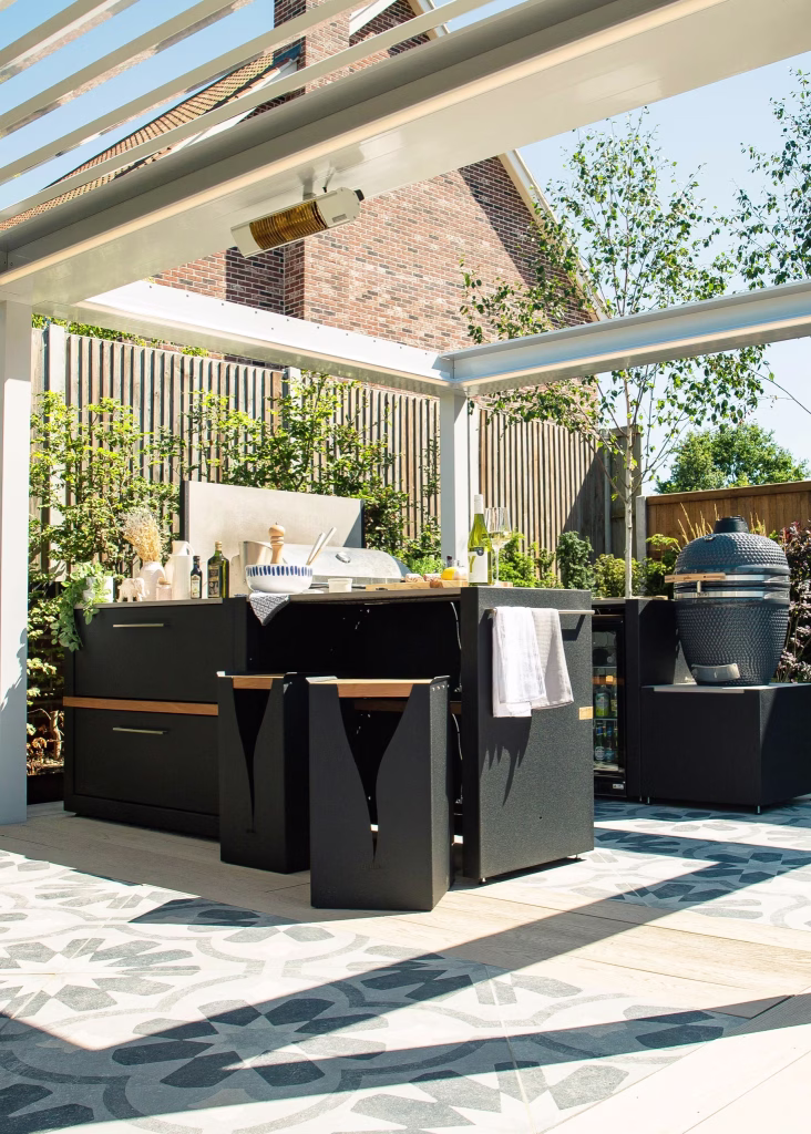 outdoor kitchen with bar table and stools and gas grill station under white Caribbean pergola on patio