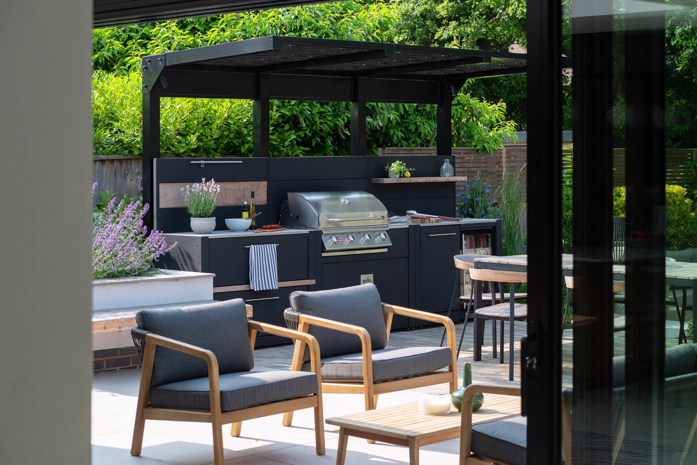 outdoor kitchen under metal covering with storage, bull gas grill station and drinks fridge and bin unit