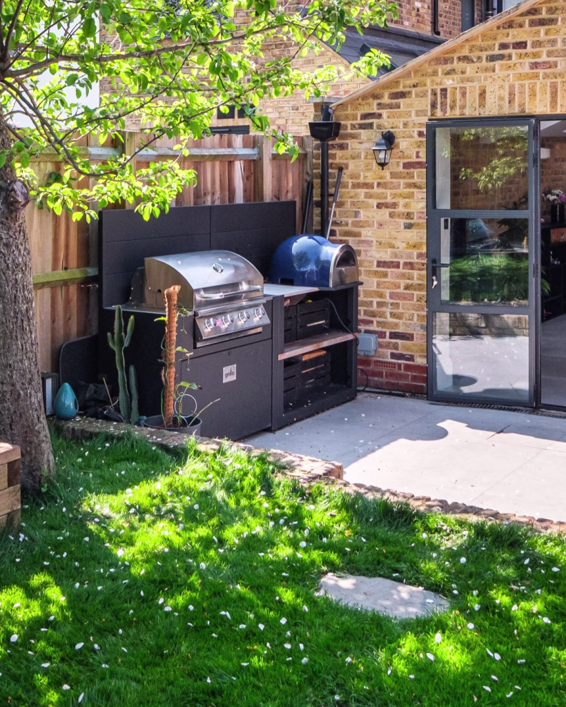 small outdoor kitchen on patio with bull gas grill station, pizza oven and storage
