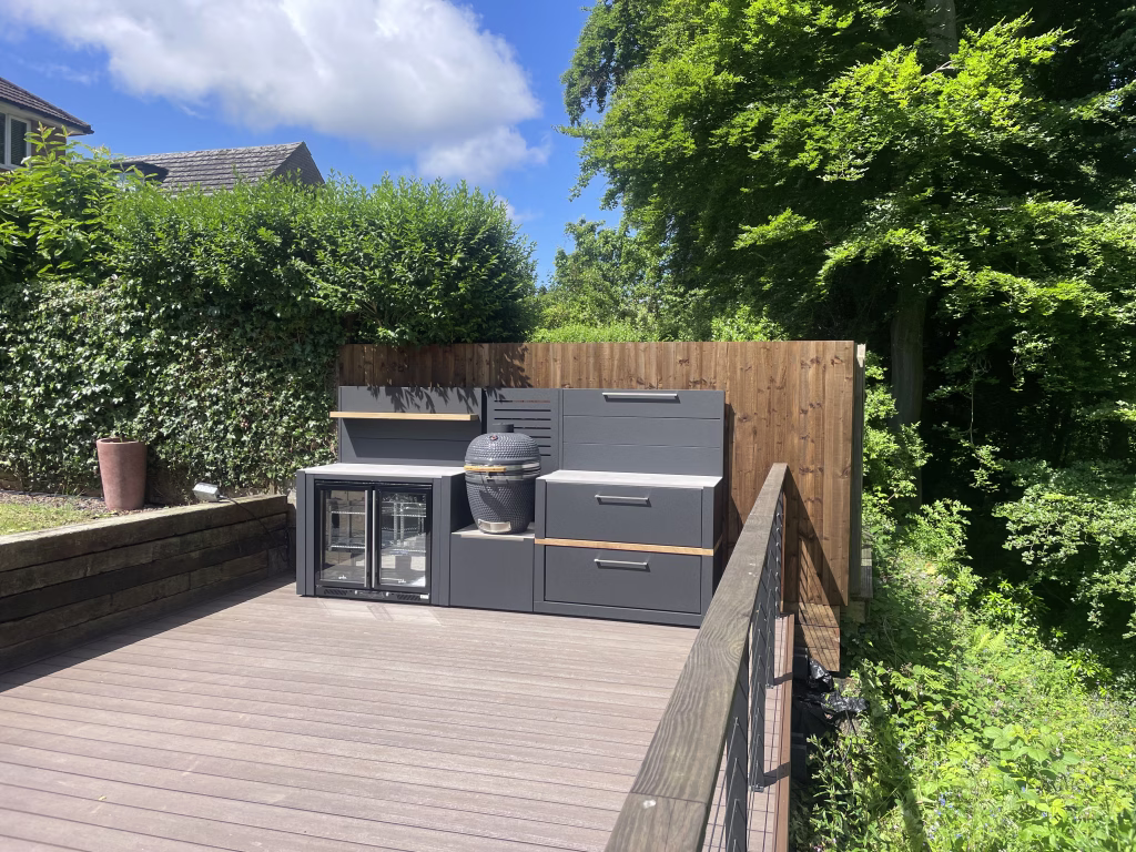 Outdoor kitchen on decking with double drinks fridge, gusto charcoal bbq and storage cabinet